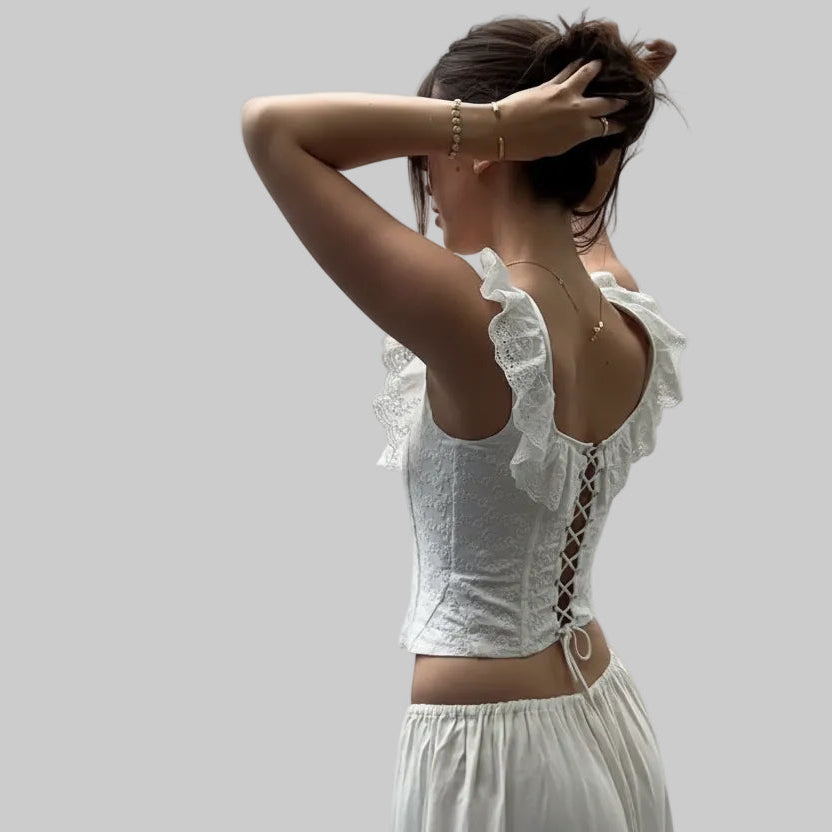 Woman wearing a white lace top and skirt on a street.