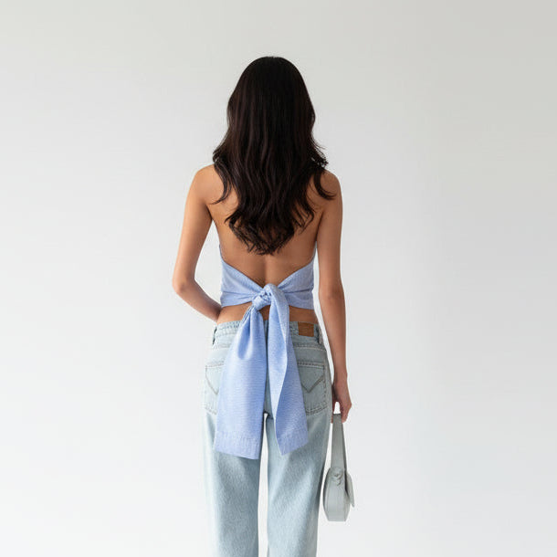 Person wearing a halter top with a blue tie detail in an indoor setting