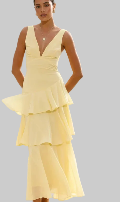 Woman wearing a yellow ruffled dress on a gray background