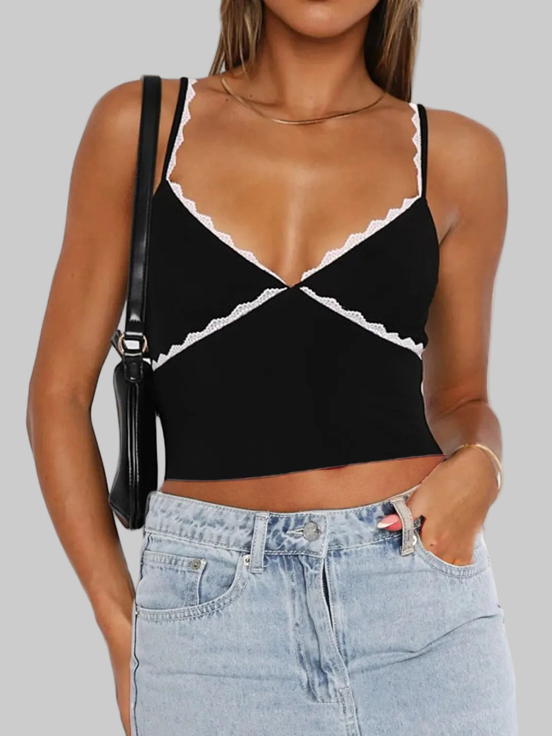 Black crop top with lace details worn by a person, with a white background