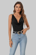Woman wearing a black sleeveless top and blue jeans with a gold belt.