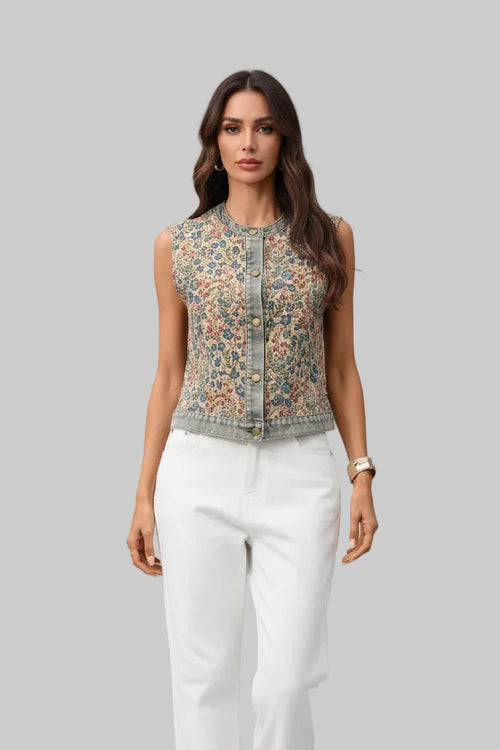 Woman wearing a sleeveless floral top and white pants on a gray background