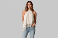 Woman wearing a white halter top with lace trim on a neutral background