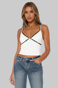 White tank top with black lace details worn by a person, with a white background